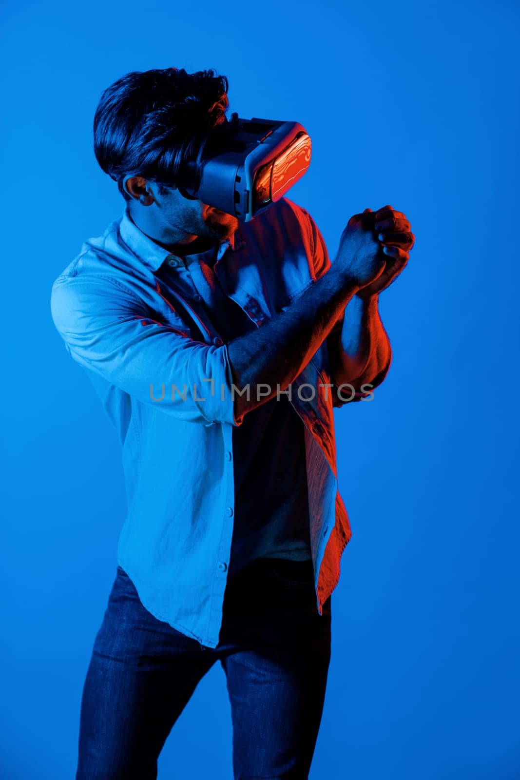 Caucasian man with VR glasses equipment moving in golf playing gesture while standing at neon background. Professional gamer enter in virtual world with futuristic technology innovation. Deviation.