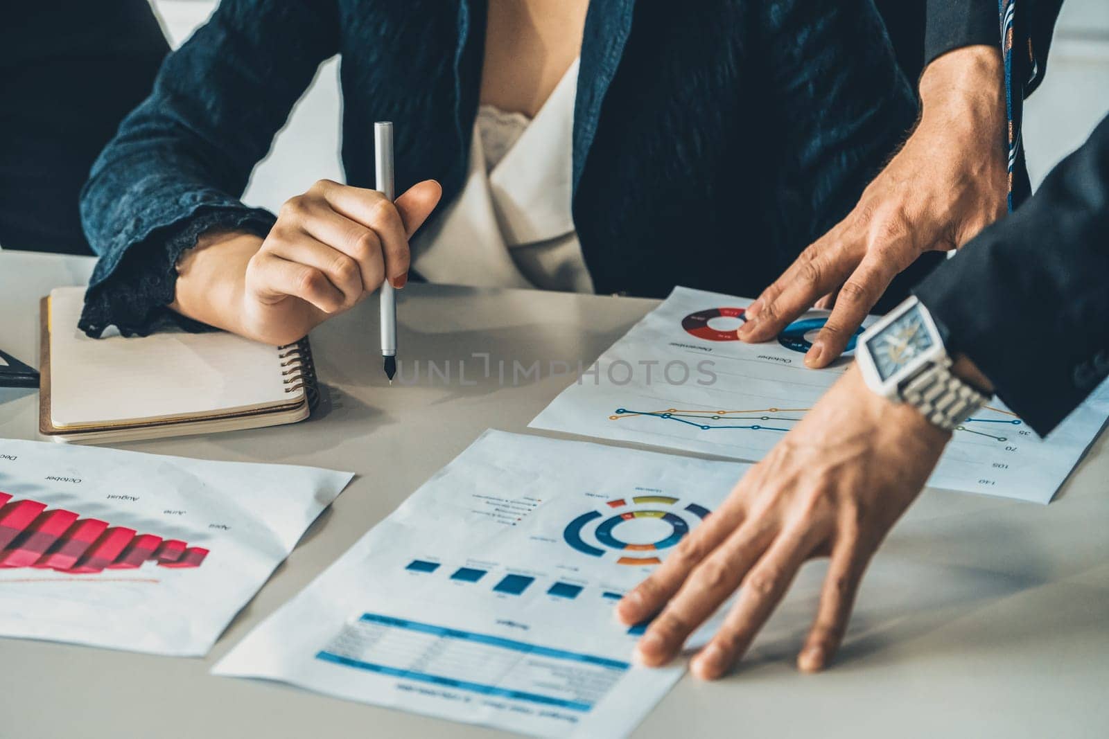 Businessman and businesswoman in meeting working with many financial statement document on desk. Concept of busy business profit analysis and brainstorm. Close up shot at people hands and papers. uds