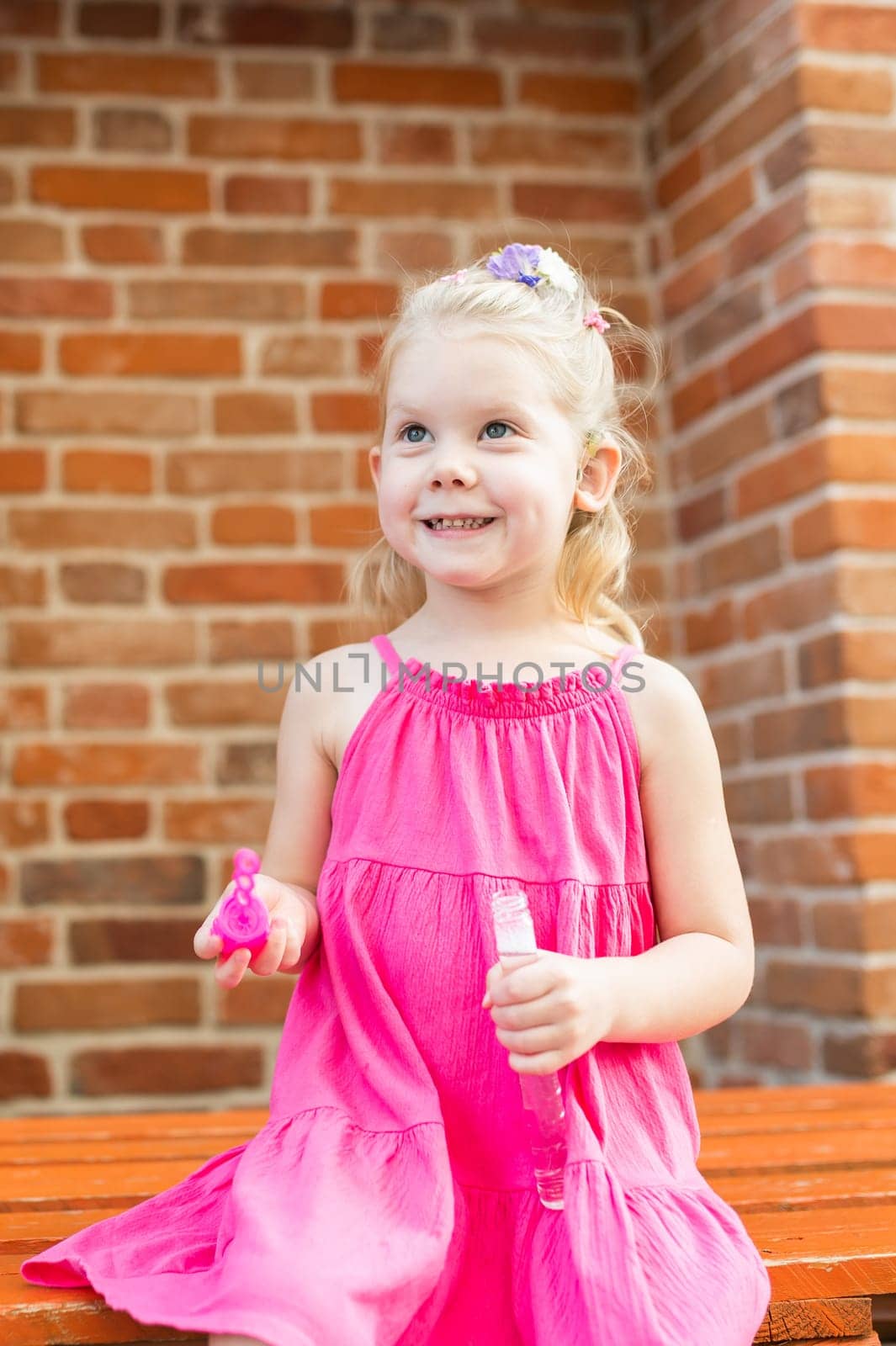 Child girl walks and have fun outdoor with cochlear implant on the head. Hearing aid and treatment concept. Copy space vertical.