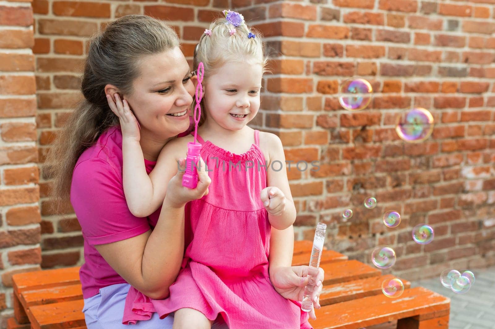 Mother holds and have fun her child with hearing aids and cochlear implants summer outdoor . Deaf and health concept. Diversity and inclusion. Copy space.