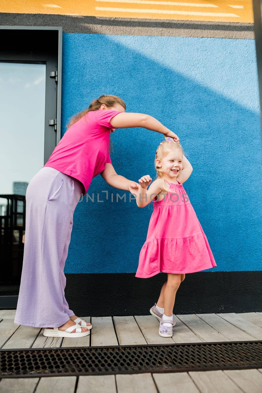 Blonde little girl with cochlear implant playing with her mother outdoor. Hear impairment deaf and health concept. Diversity and inclusion. Copy space by Satura86