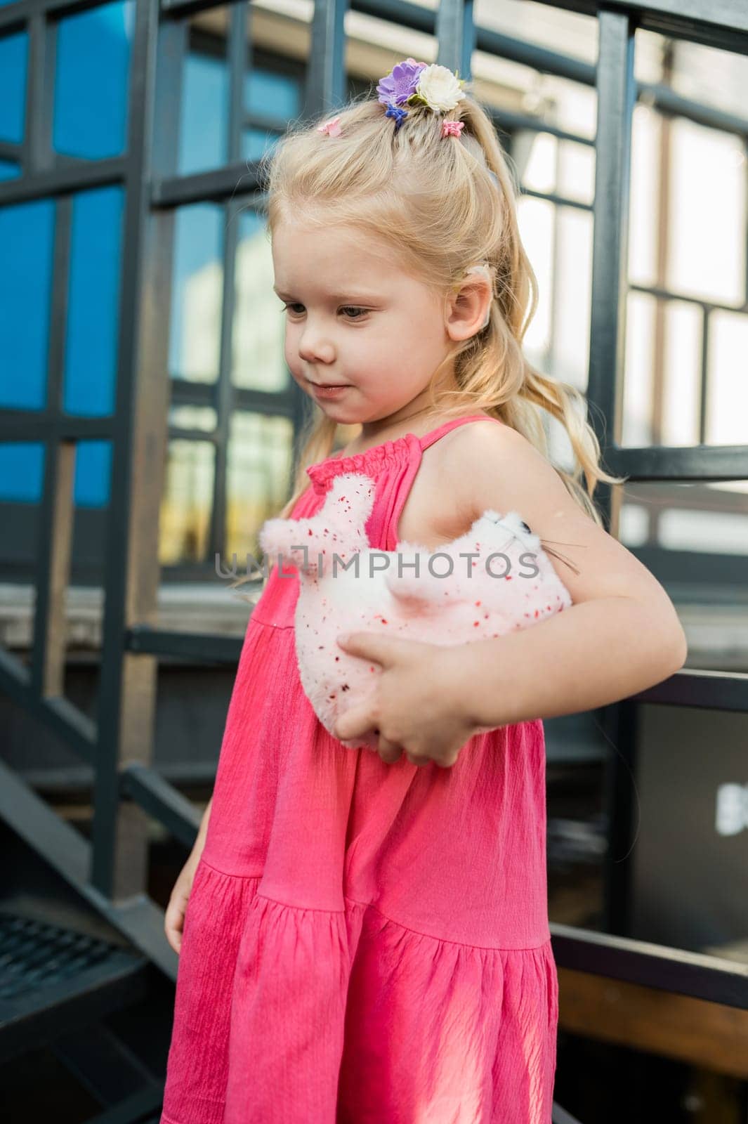 Child girl walks and have fun outdoor with cochlear implant on the head. Hearing aid and treatment concept. Copy space vertical.