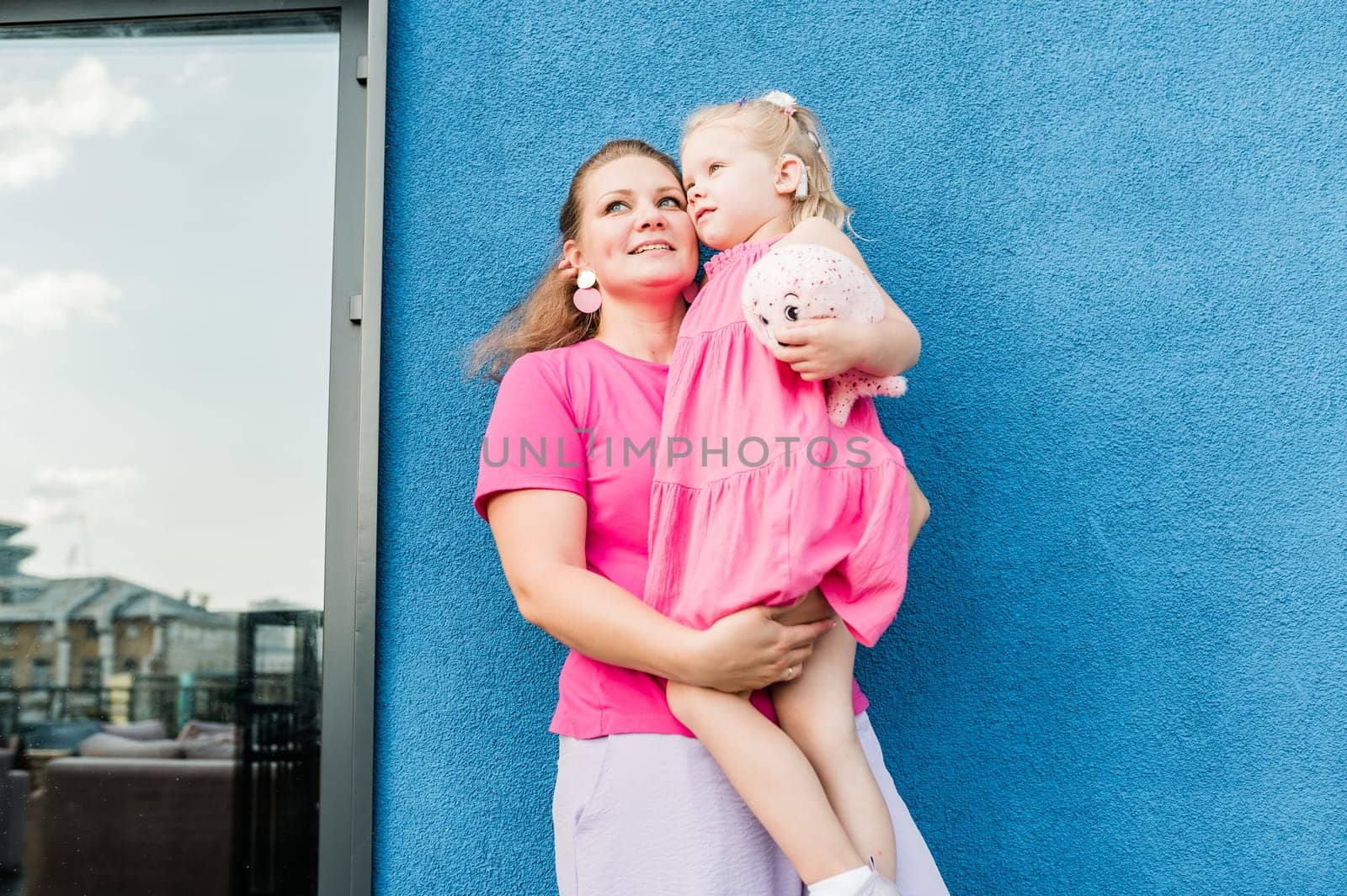 Mother holds and have fun her child with hearing aids and cochlear implants summer outdoor . Deaf and health concept. Diversity and inclusion. Copy space.