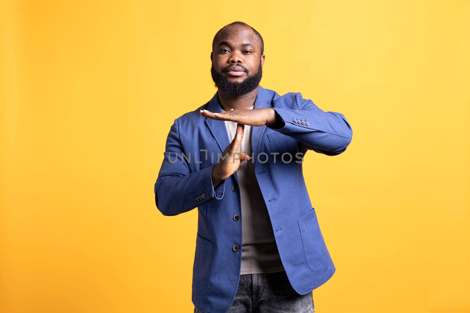 Portrait of assertive man asking for timeout, doing hand gestures, feeling fatigued. Unhappy person doing vehement pause sign gesturing, wishing for break, studio background