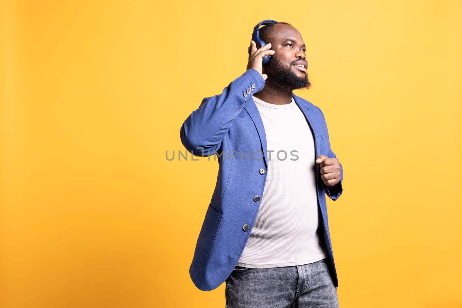Man having fun listening to music on headset, dancing around, studio background by DCStudio