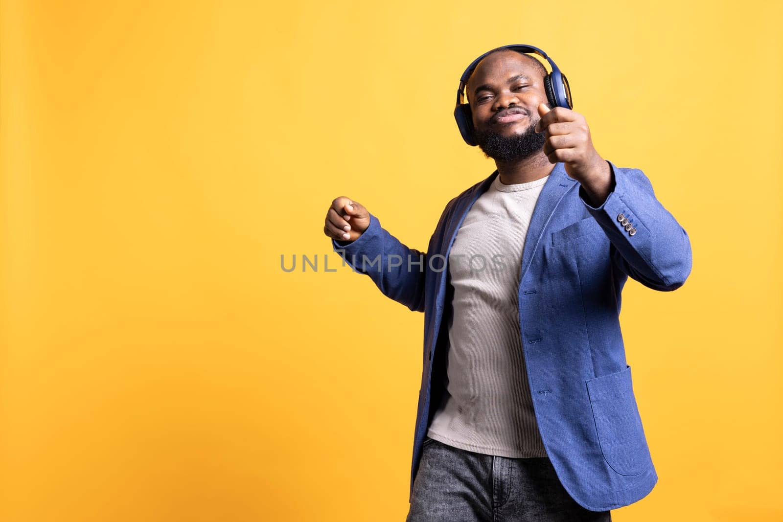 Happy african american person having fun, dancing on rhythm, enjoying leisure time. Cheerful BIPOC man entertaining himself doing funky movements on music, studio background, camera A
