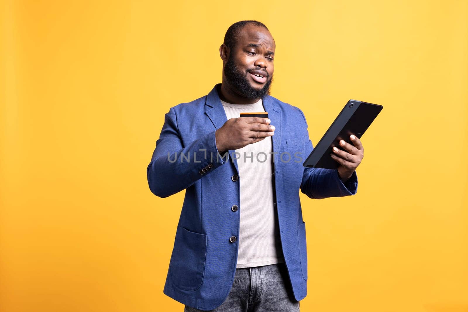 African american man adding payment method on website, isolated over studio background. Cheerful man excited to do online shopping, carefully typing credit card information