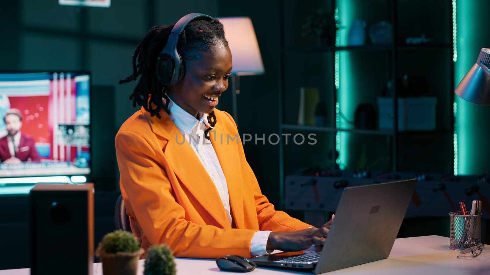 African american girl jamming on music and writing reports for her final bachelor essay, having fun with songs on headset. Student preparing for exams with class notes and materials. Camera A.