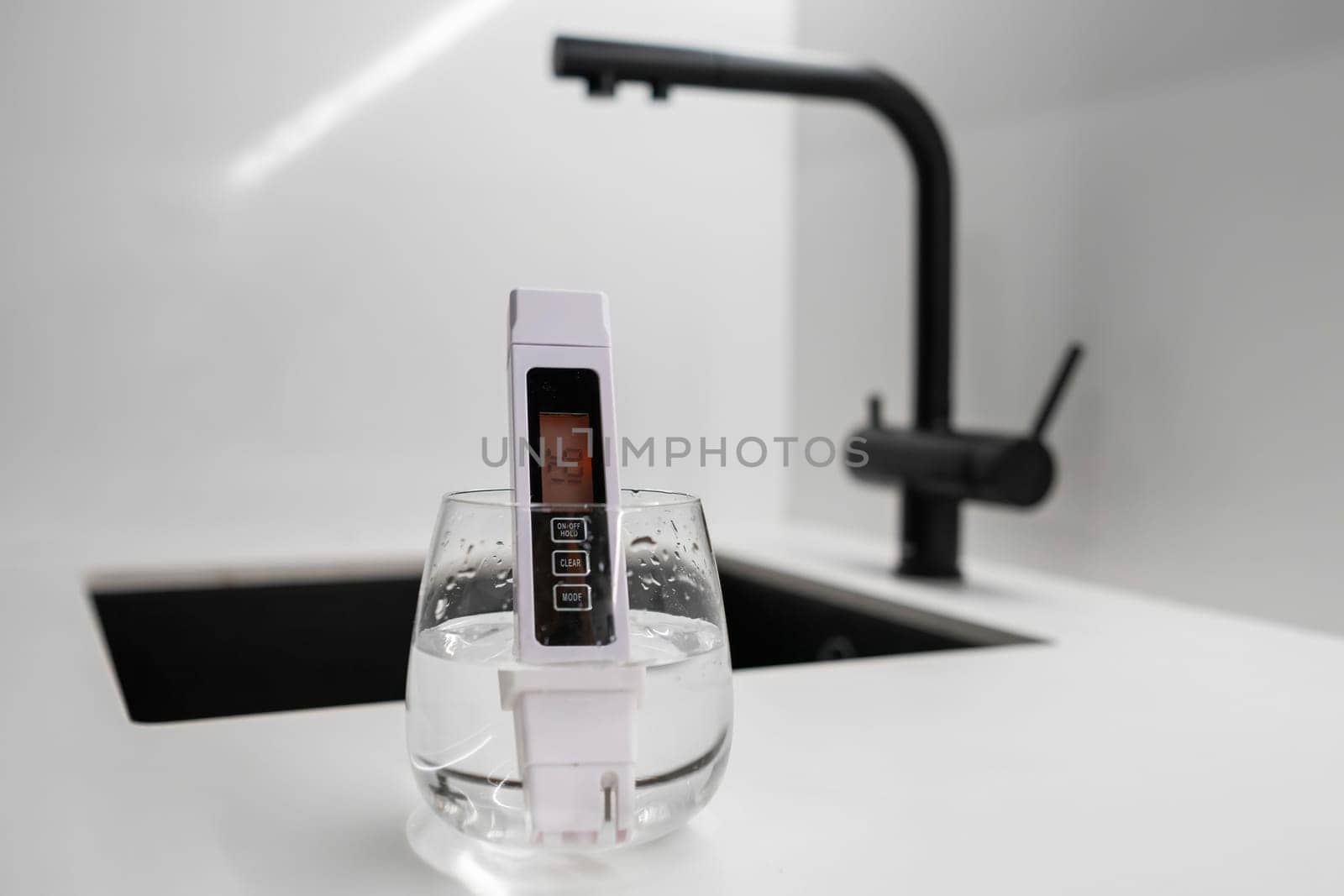 Conductometer or TDS water quality meter is immersed in a beaker of water to check purity by vladimka