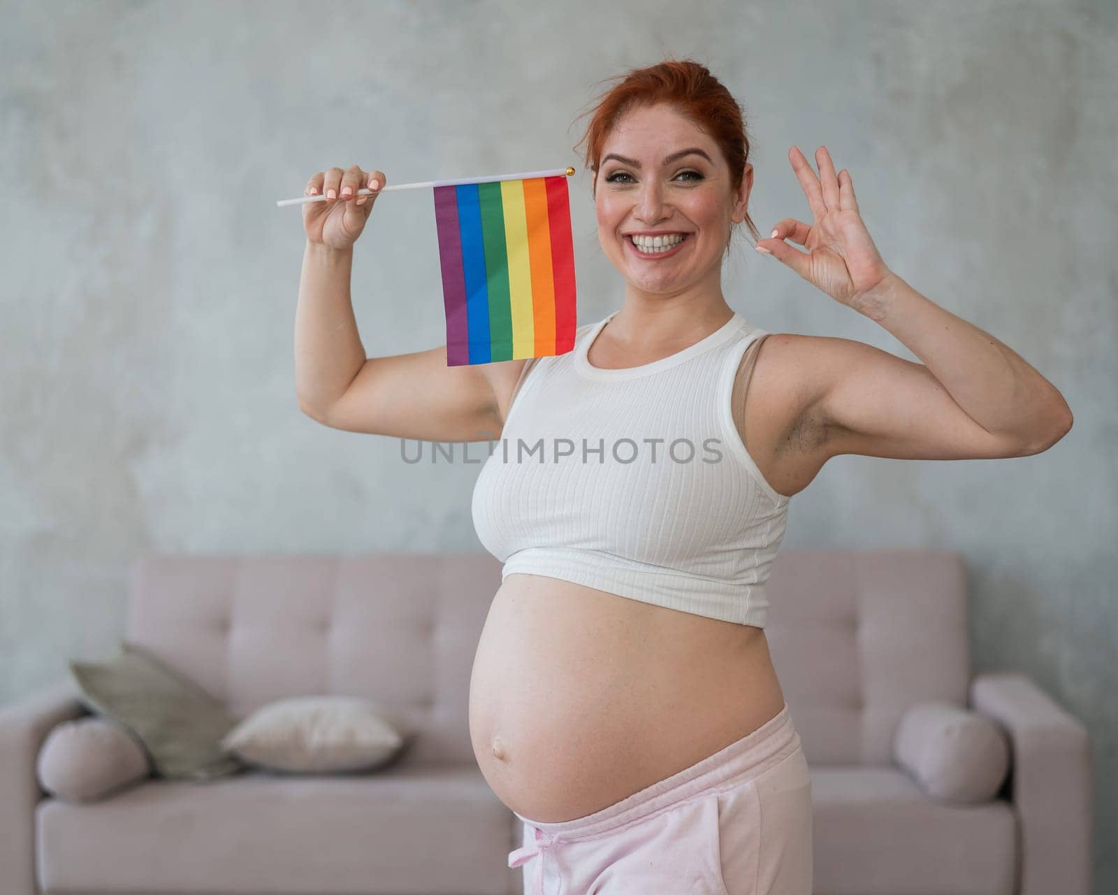 Happy pregnant woman holding rainbow flag and showing thumbs up. by mrwed54