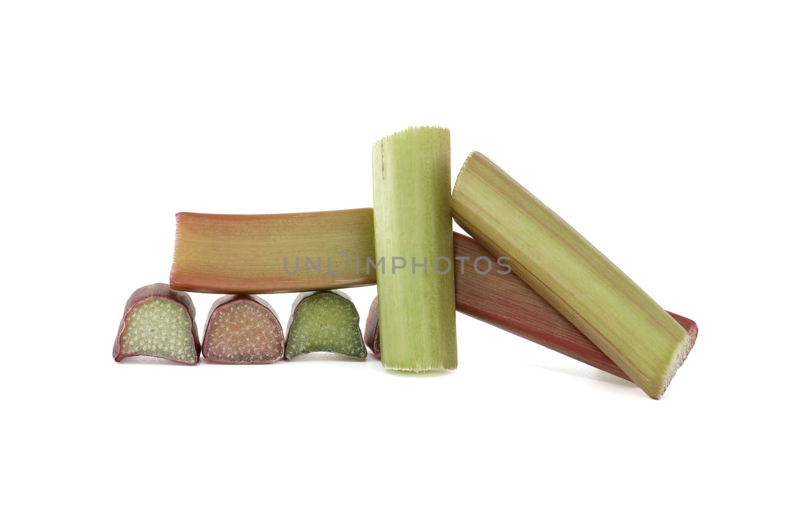 Group of rhubarb pieces in various shapes and sizes arranged in a scattered formation isolated on white background