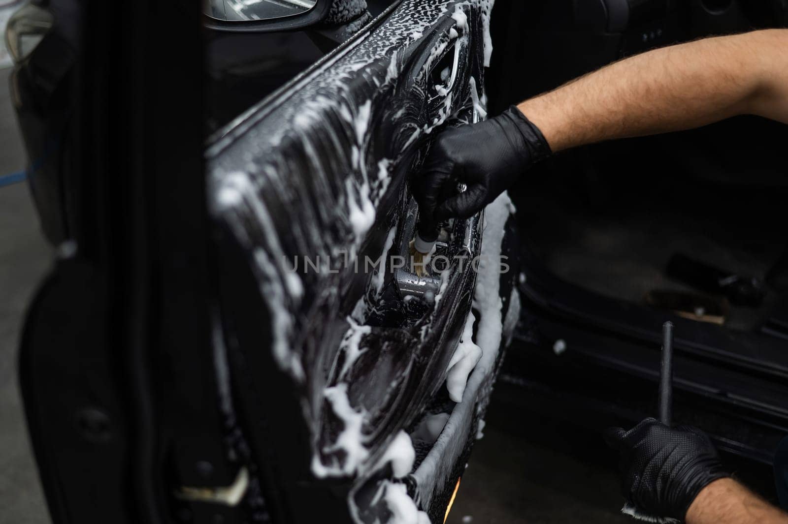 A man cleans the interior of a car with foam and a brush. Clean the door trim. by mrwed54