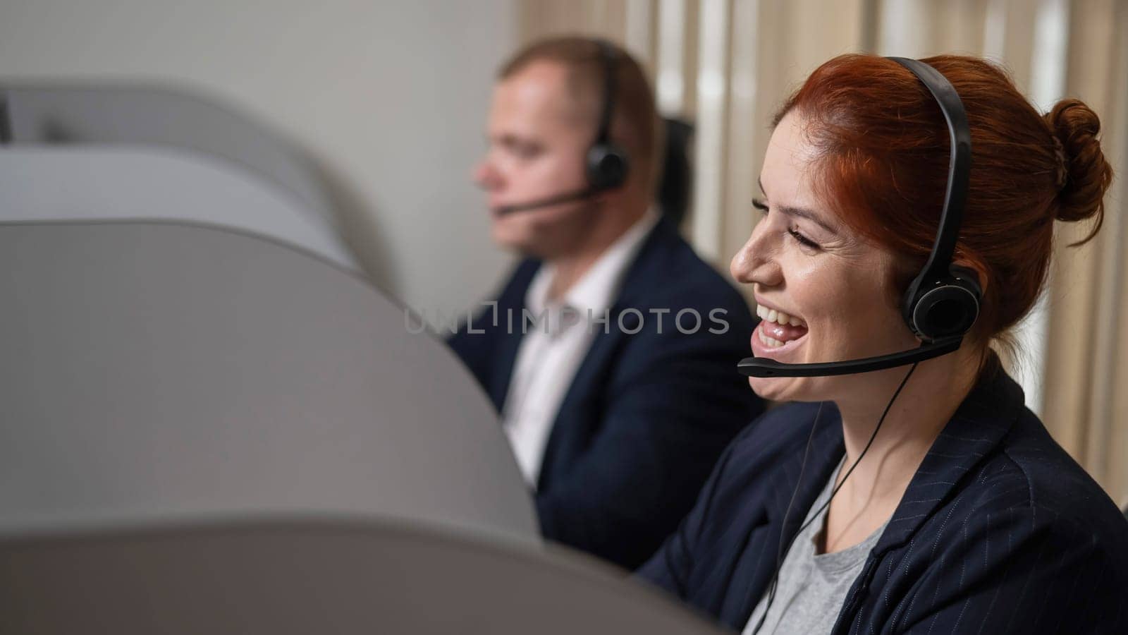 Two friendly call center employees answer customers by phone. Man and woman woman talking on a headset in the office