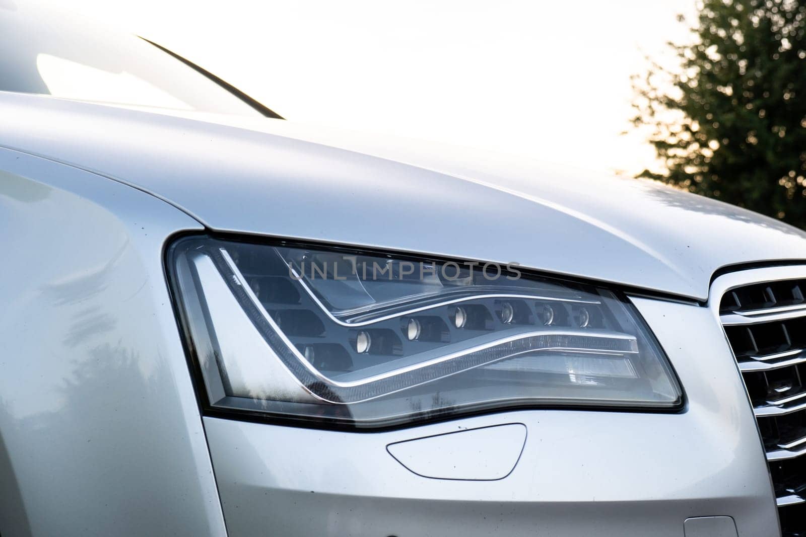 Clean car after Washing luxury silver car. Sedan car exterior of modern luxury car during sunset on highway road. Details of front headlamp. Prestige sport automobile