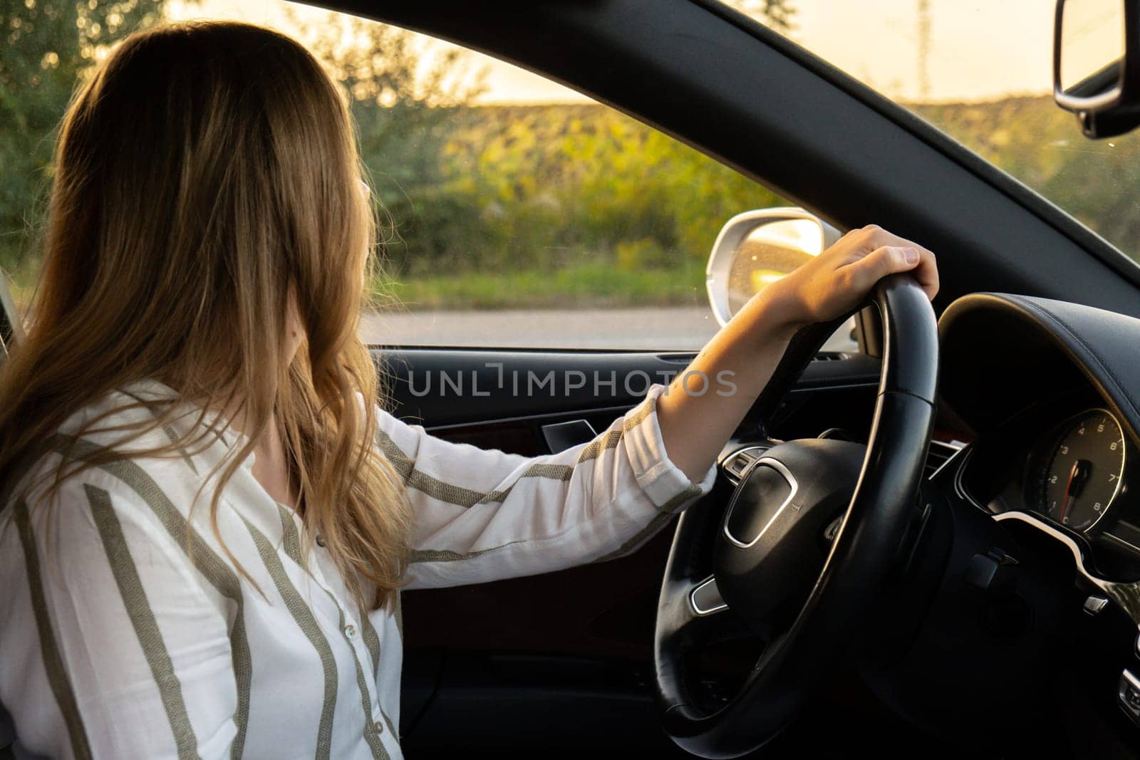 Happy young woman driving car. Business woman checking road automobile. Unsafely risky driving. Concept of multitasking