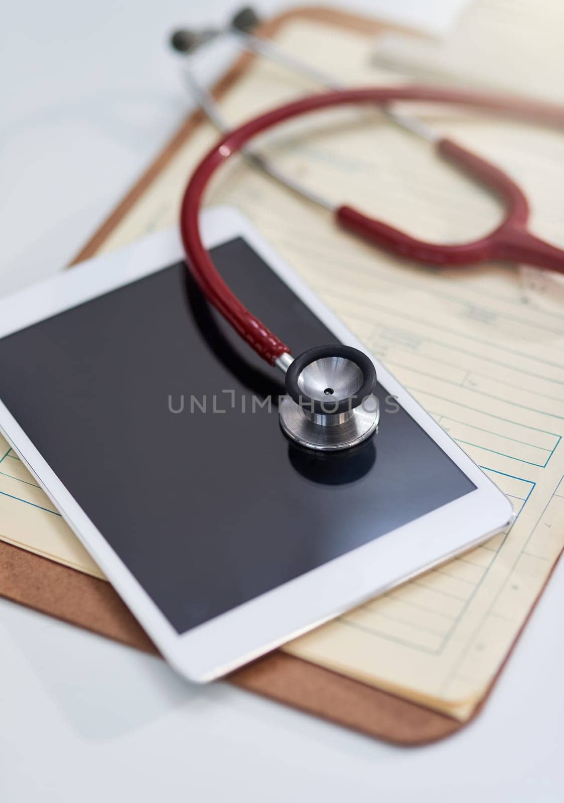 Hospital, clinic and tablet with stethoscope on desk for medical website, telehealth and research. Healthcare, cardiology and digital tech, equipment and clipboard for online consulting service by YuriArcurs