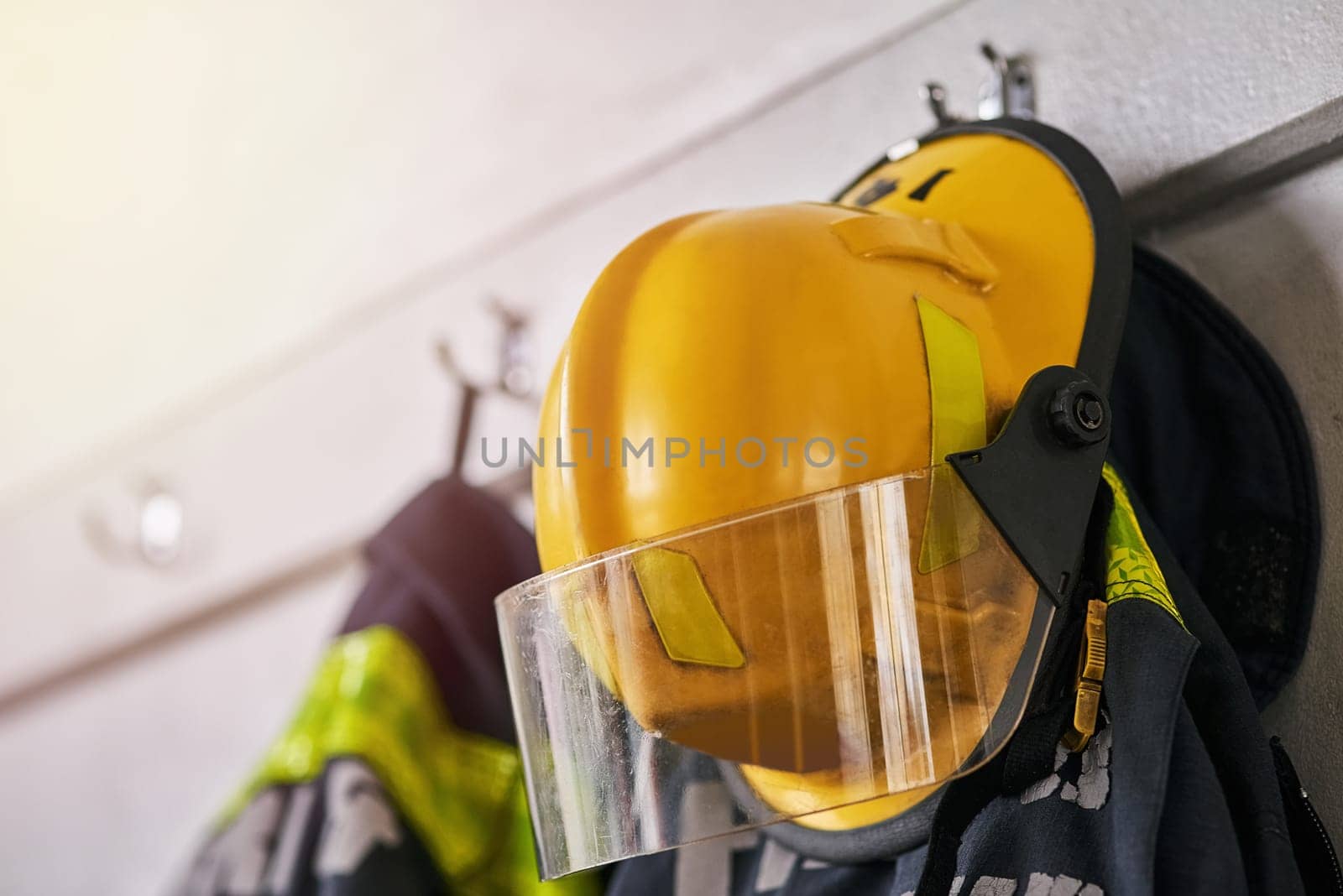 Helmet, clothes and fire fighter for safety gear in emergency service, security and hero, courage or risk. Rescue uniform in department with protection and ppe on hanger, ready for danger or accident by YuriArcurs