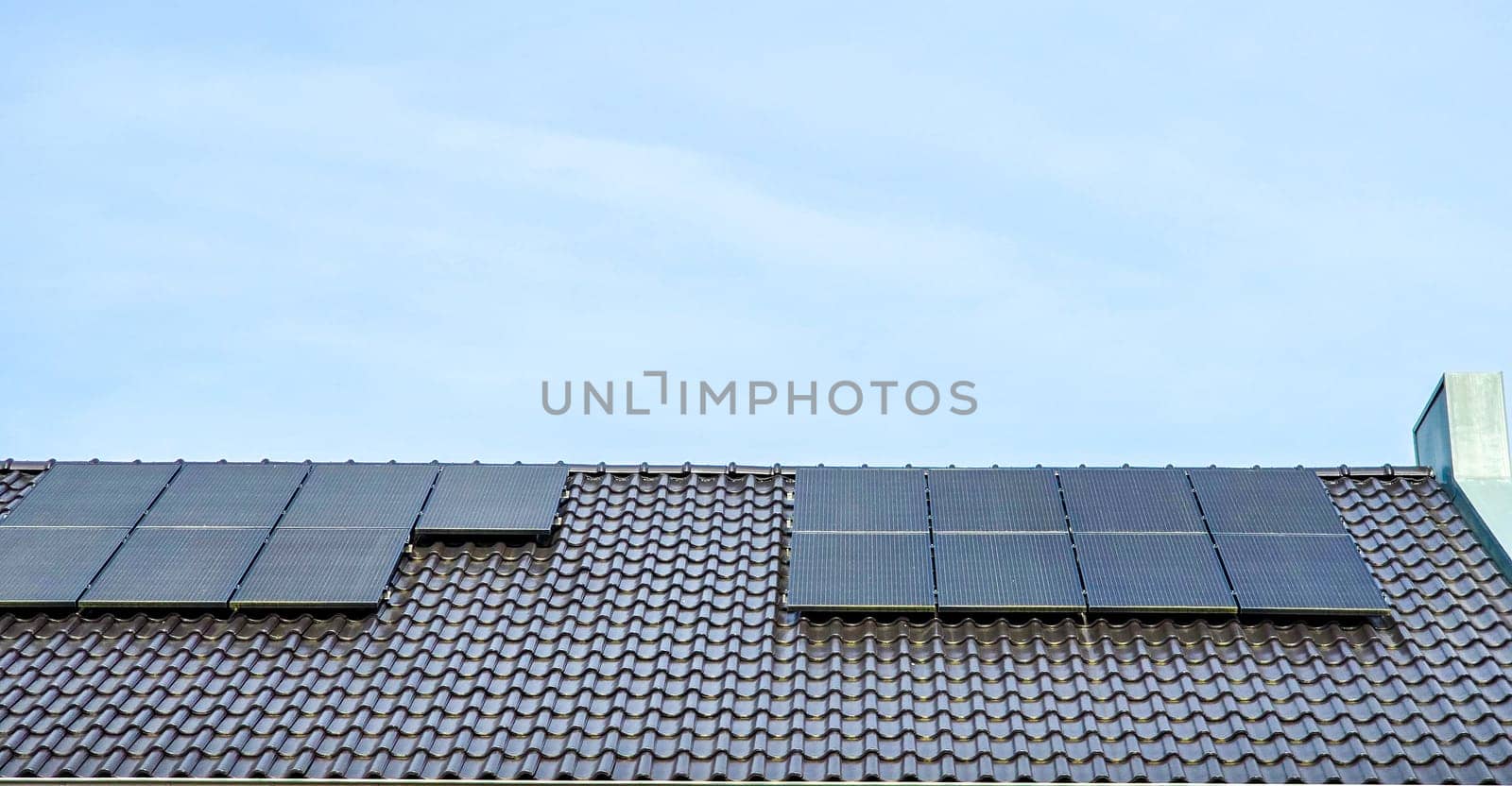 Newly built houses with black solar panels on the roof against a sunny sky Close up of new house with black solar panels. Zonnepanelen, Zonne energie, Translation: Solar panel, Sun Energy