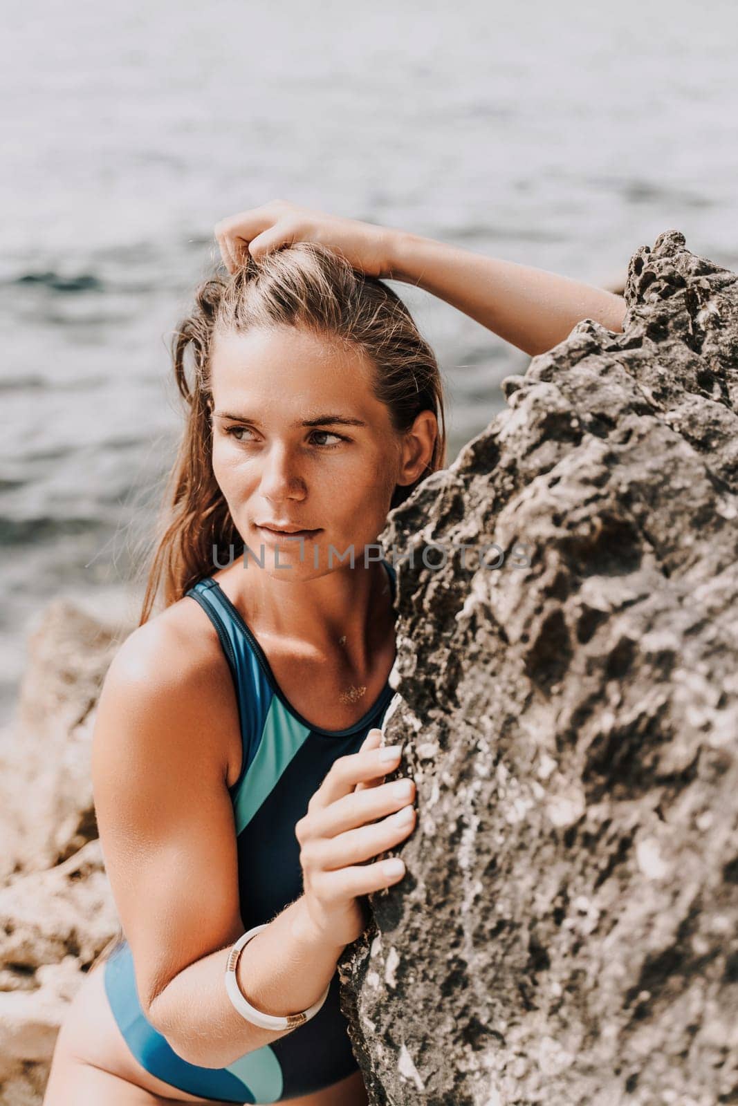 Woman beach vacation photo. A happy tourist in a blue bikini enjoying the scenic view of the sea and volcanic mountains while taking pictures to capture the memories of her travel adventure