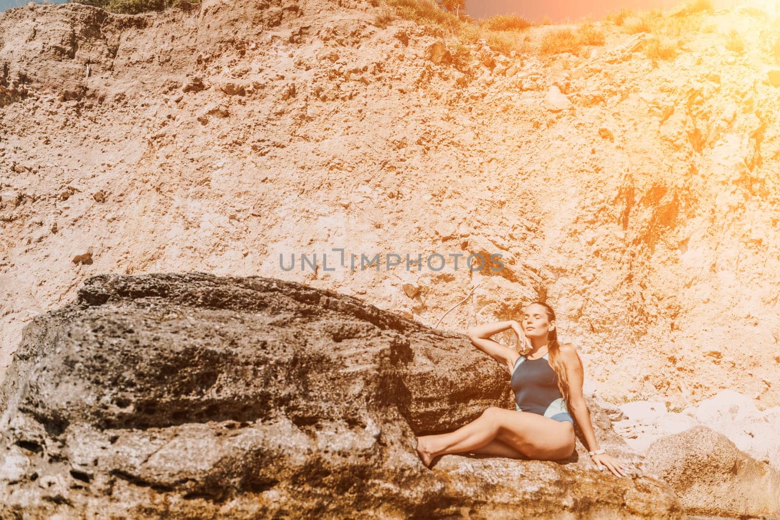 Woman travel summer sea. A happy tourist in a blue bikini enjoying the scenic view of the sea and volcanic mountains while taking pictures to capture the memories of her travel adventure