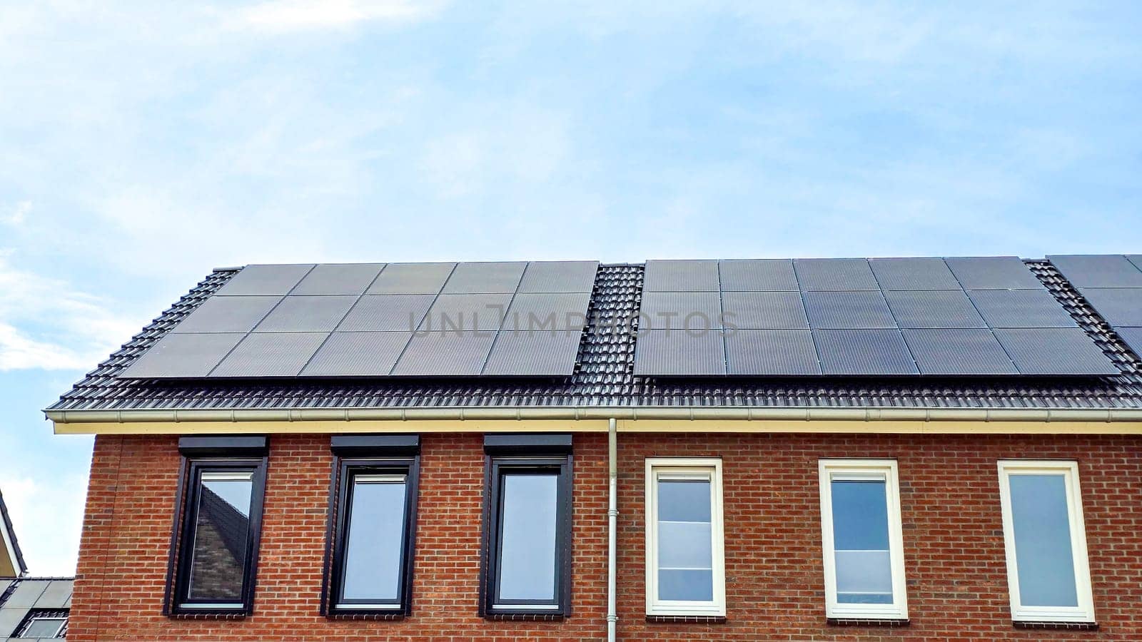 Newly built houses with black solar panels on the roof against a sunny sky Close up of new building with black solar panels.