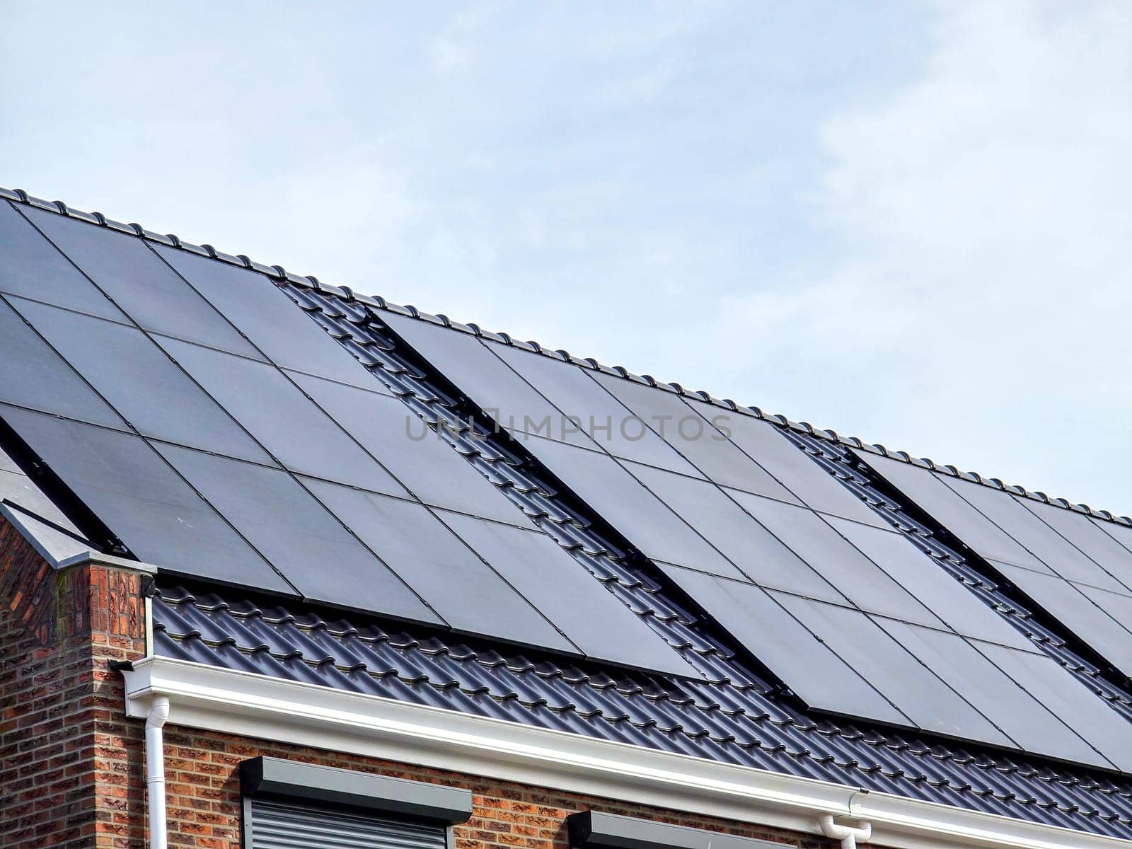 Newly build houses with solar panels attached on the roof against a sunny sky by fokkebok