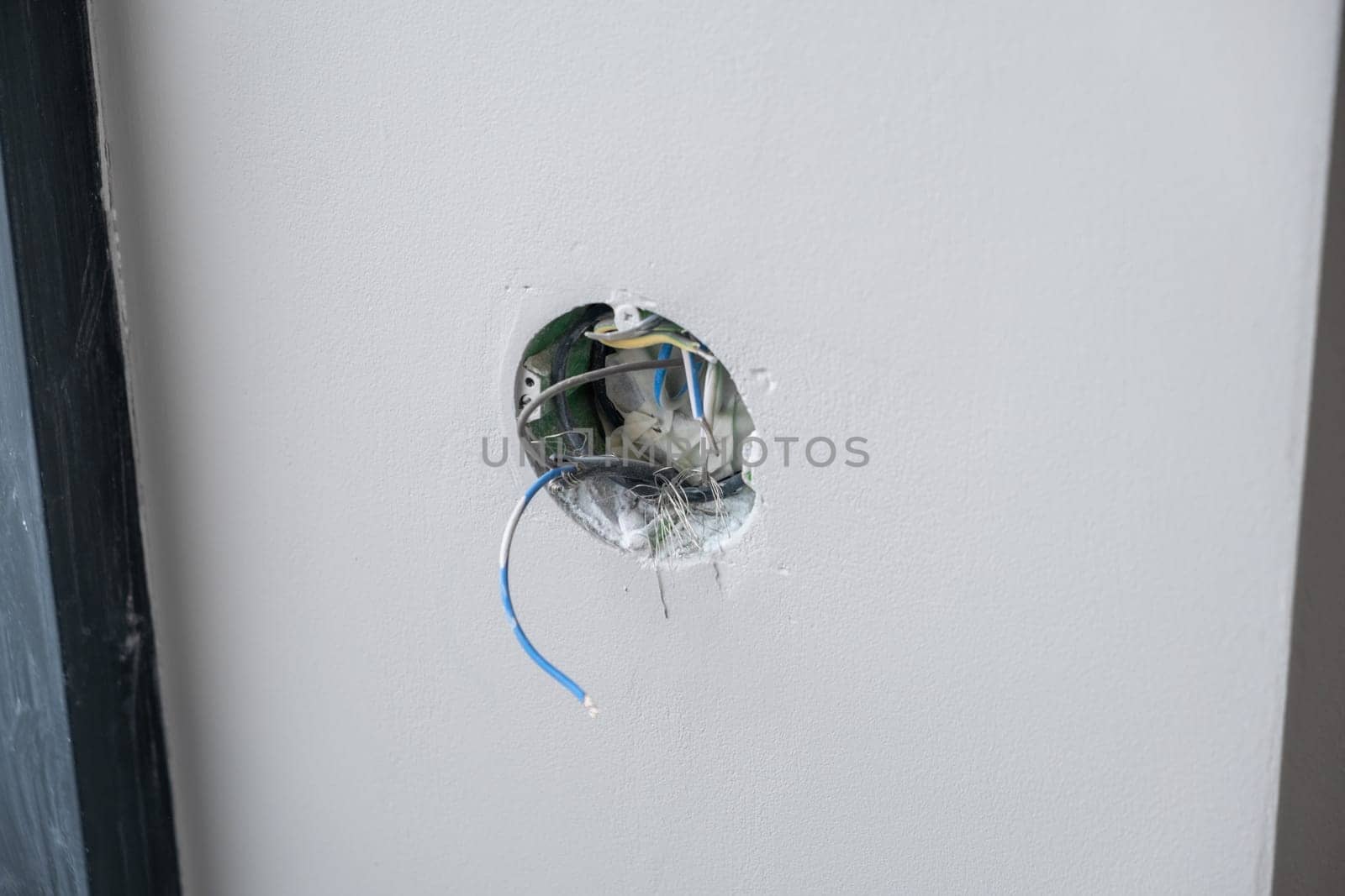 Apartment renovation. Electrical wiring. Wires sticking out of the wall. Wiring electrical cables on wall in the apartment Unfinished electrical mains outlet socket with electrical wires.