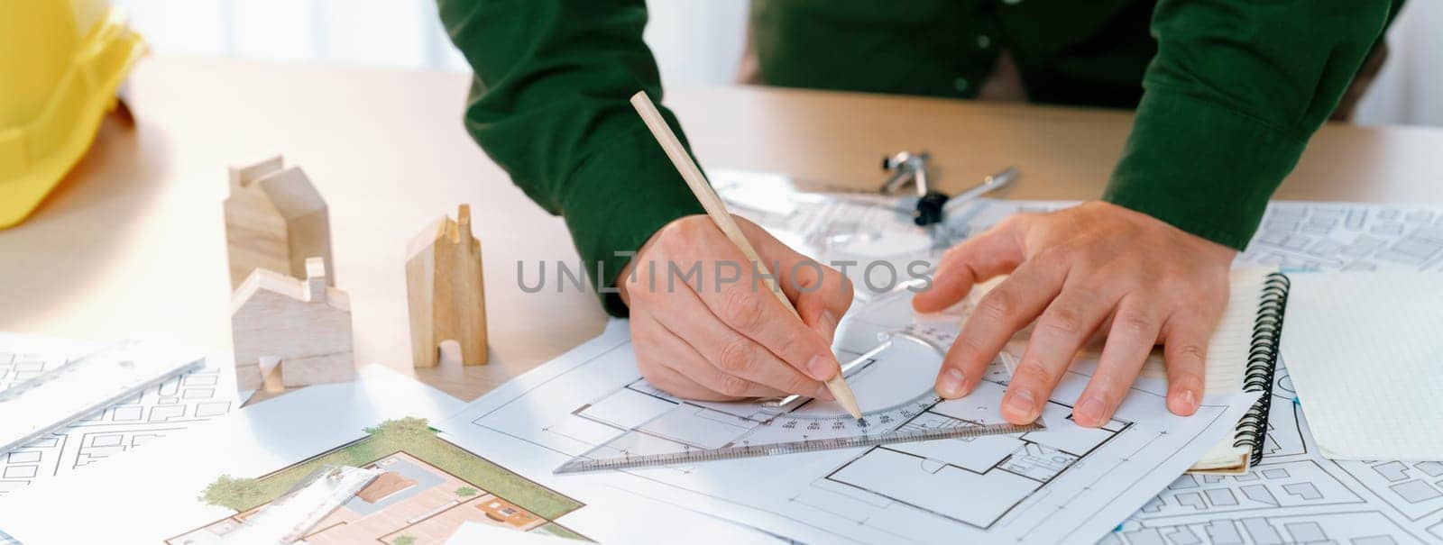 Professional engineer measuring the blueprint. Professional engineer working architectural project at studio on a table with yellow helmet and architectural equipment scatter around. Delineation.