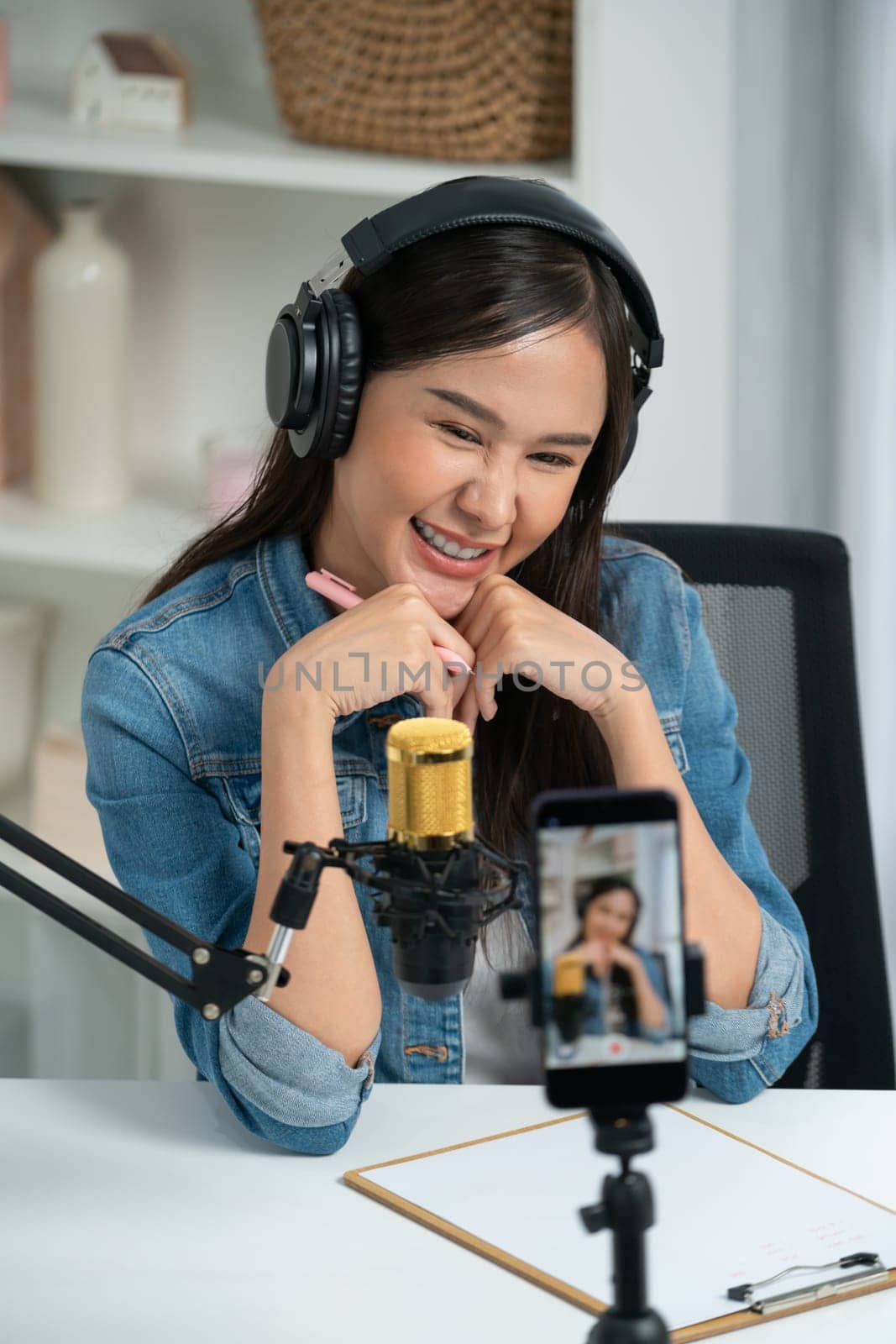 Host channel Asian influencer talking in broadcast wearing headsets on social media live on smartphone recording online, greeting listeners with coaching life or business at modern studio. Stratagem.