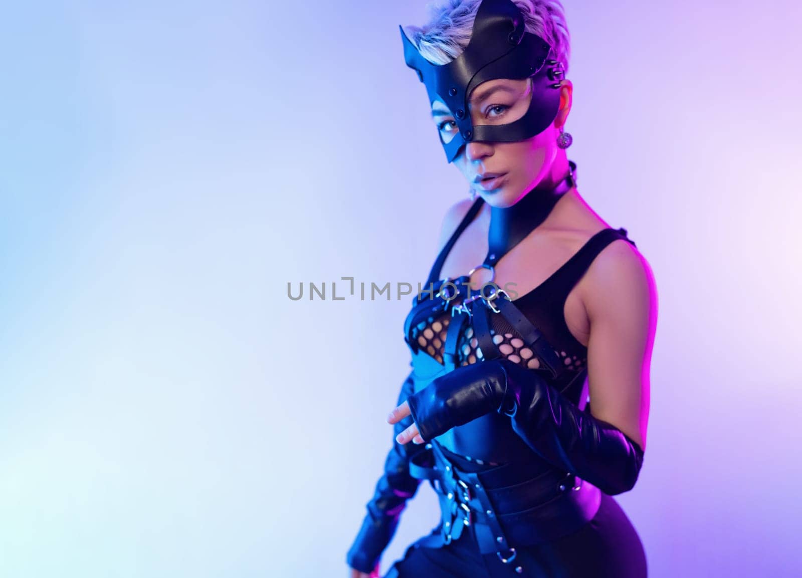 A sexy girl in the erotic image of a catwoman in leather bdsm straps and a mask poses against a copy paste background on a beautiful neon background by Rotozey