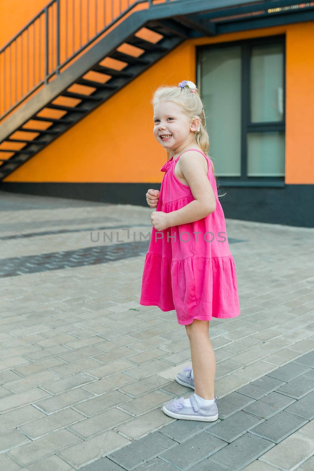 Child girl with hearing aid and cochlear implantation system. Kid with hearing problems walks outdoor in summer. Inclusion and diversity