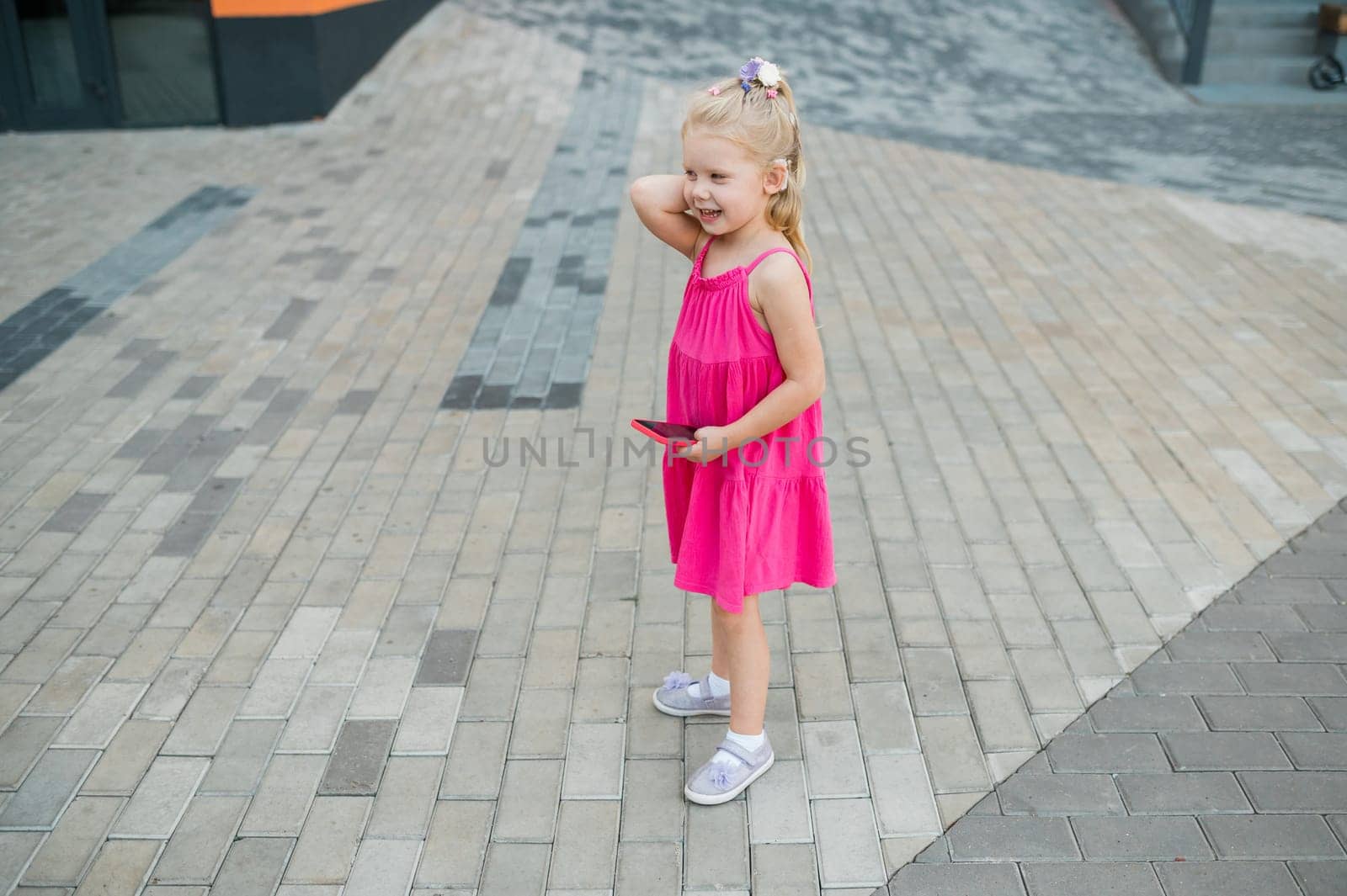 Child walks with cochlear implant hearing aid in summer street. Inclusion and modern technologies for treating hearing loss.