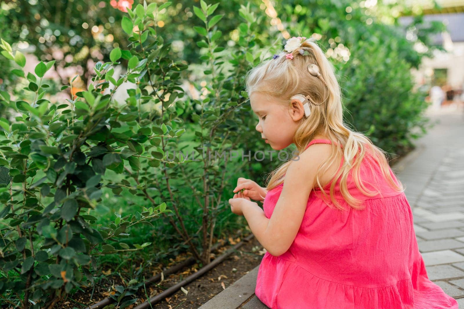 Child walks with cochlear implant hearing aid in summer street. Inclusion and modern technologies for treating hearing loss.