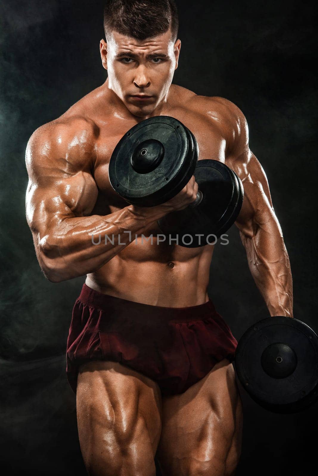 Brutal strong muscular bodybuilder athletic man pumping up muscles with dumbbell on black background. Workout bodybuilding concept. Copy space for sport nutrition ads. by MikeOrlov