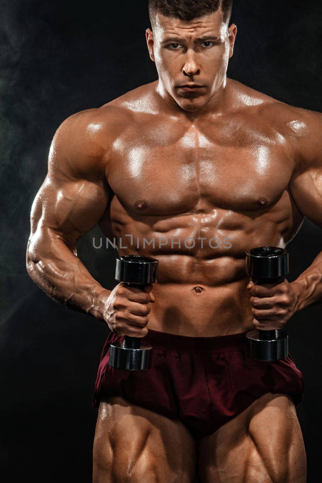 Brutal strong muscular bodybuilder athletic man pumping up muscles with dumbbell on black background. Workout bodybuilding concept. Copy space for sport nutrition ads. by MikeOrlov