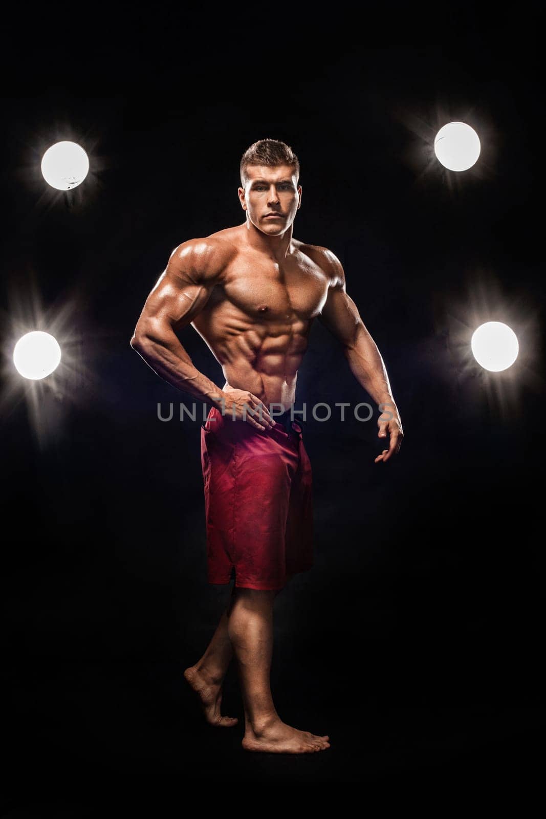 Brutal strong muscular bodybuilder athlete man pumping up muscles on black background. Workout bodybuilding concept. Copy space for sport nutrition ads. by MikeOrlov