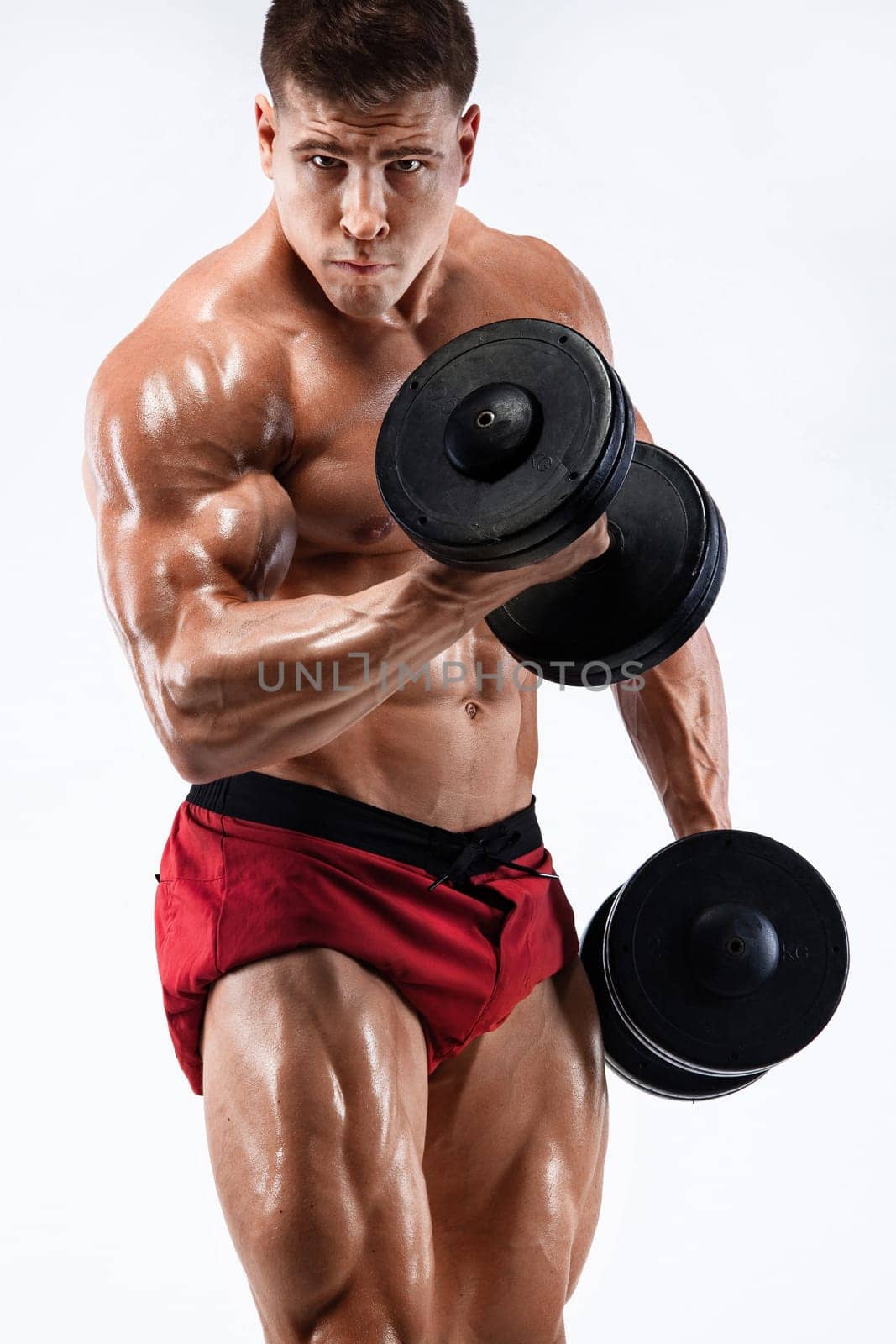 Brutal strong muscular bodybuilder athletic man pumping up muscles with dumbbell on white background. Workout bodybuilding concept. Copy space for sport nutrition ads. by MikeOrlov