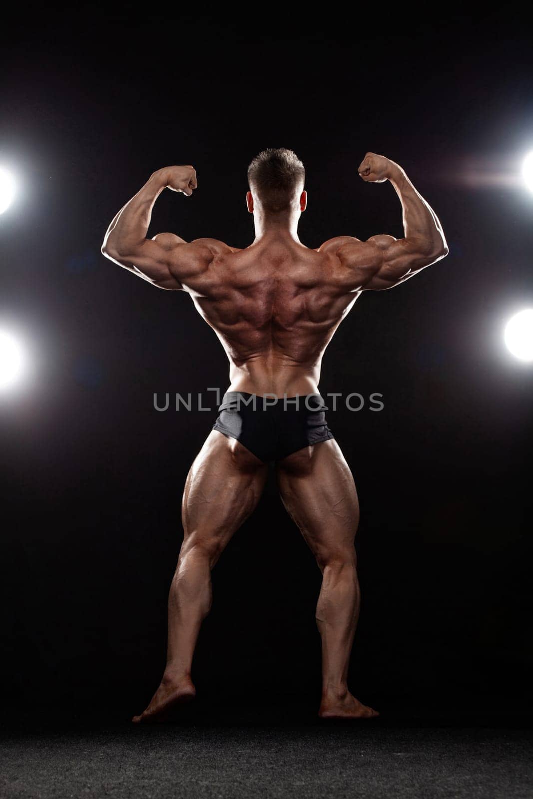 Strong muscular bodybuilder athlete man posing and pumping up muscles on black background. Workout bodybuilding concept. by MikeOrlov