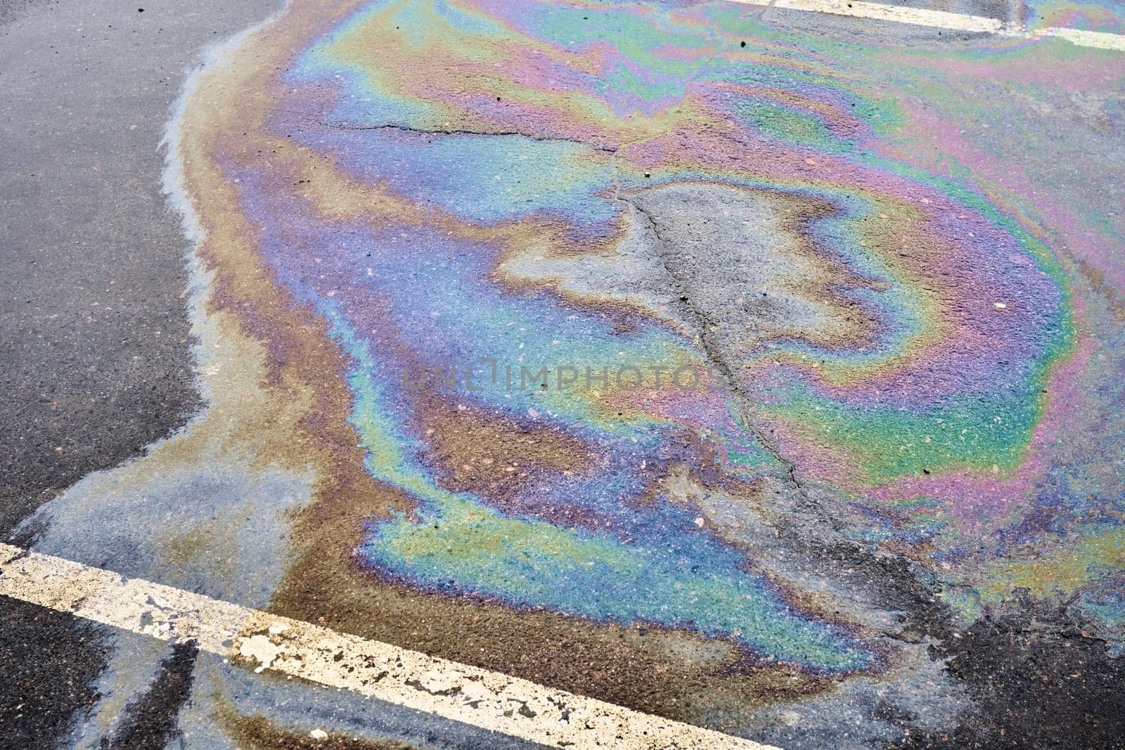 Wet asphalt parking lot with a visible oil spill and dividing line