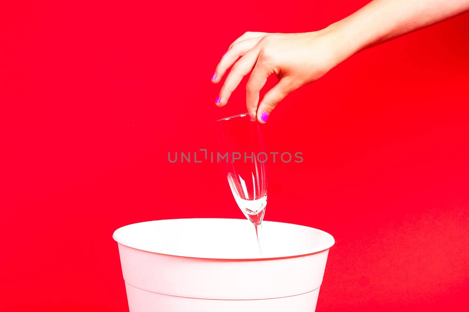 A woman is discarding a glass into a trash can by Zelenin