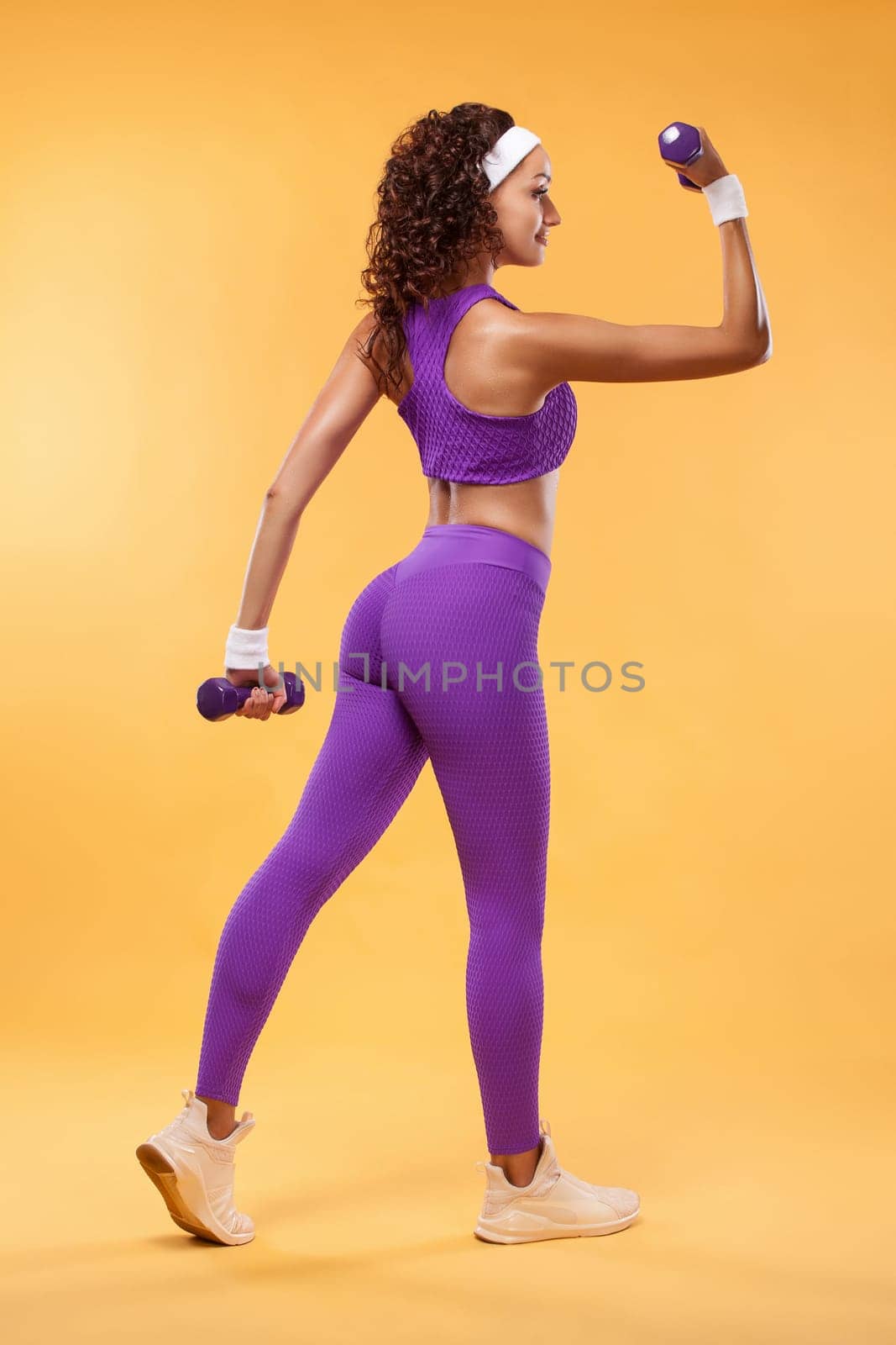 Sporty beautiful woman with dumbbells makes fitness exercising at white background to stay fit by MikeOrlov