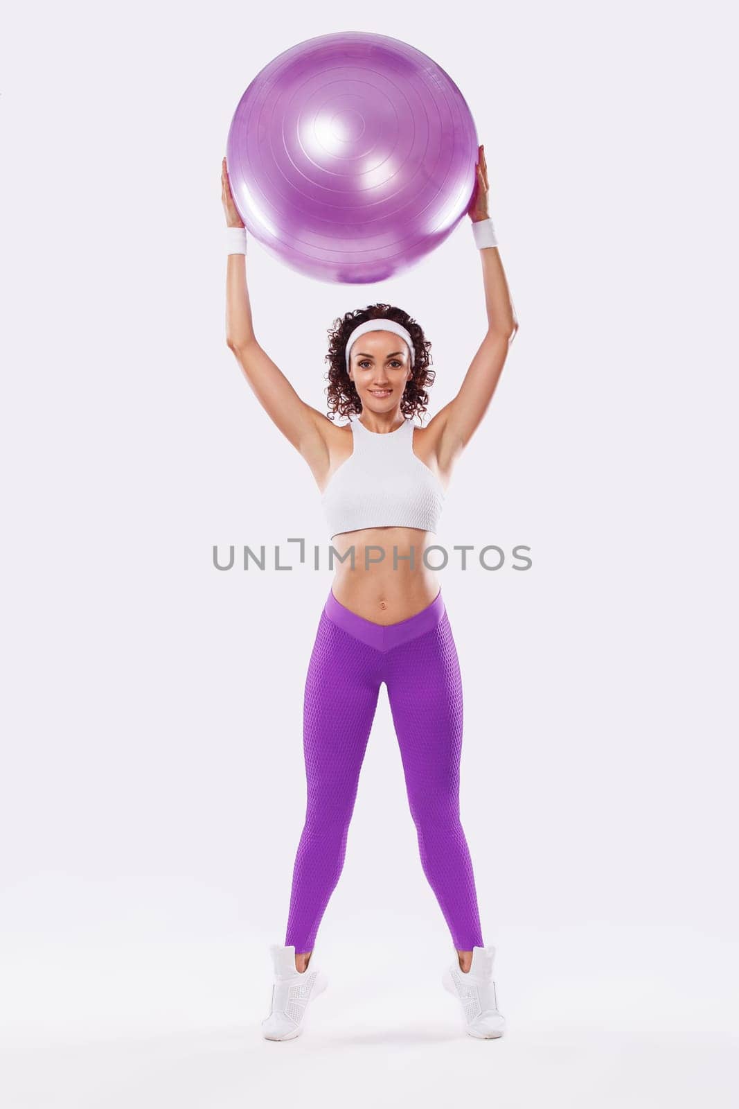Young sport woman with pink fitball on white background