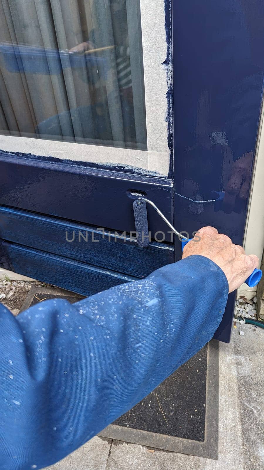 painting a door with blue paint with a roller by compuinfoto