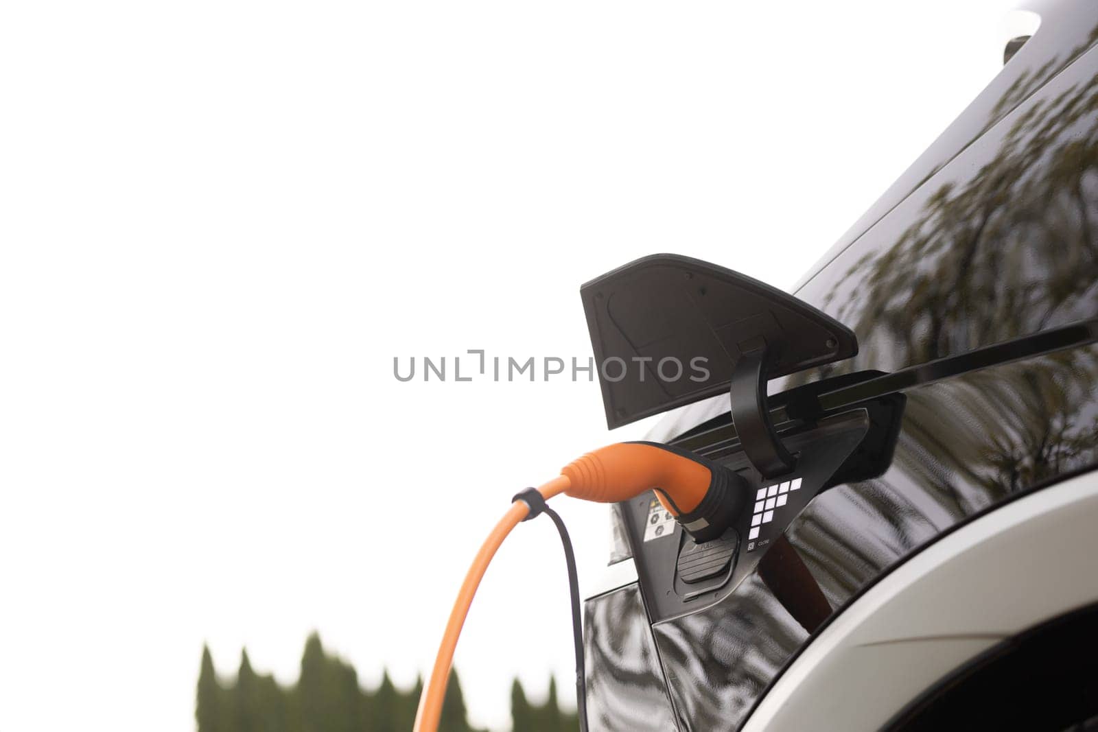 Electric vehicle charging port plugging in EV modern car. Save ecology alternative energy sustainable of future. Electric car charging port by uflypro