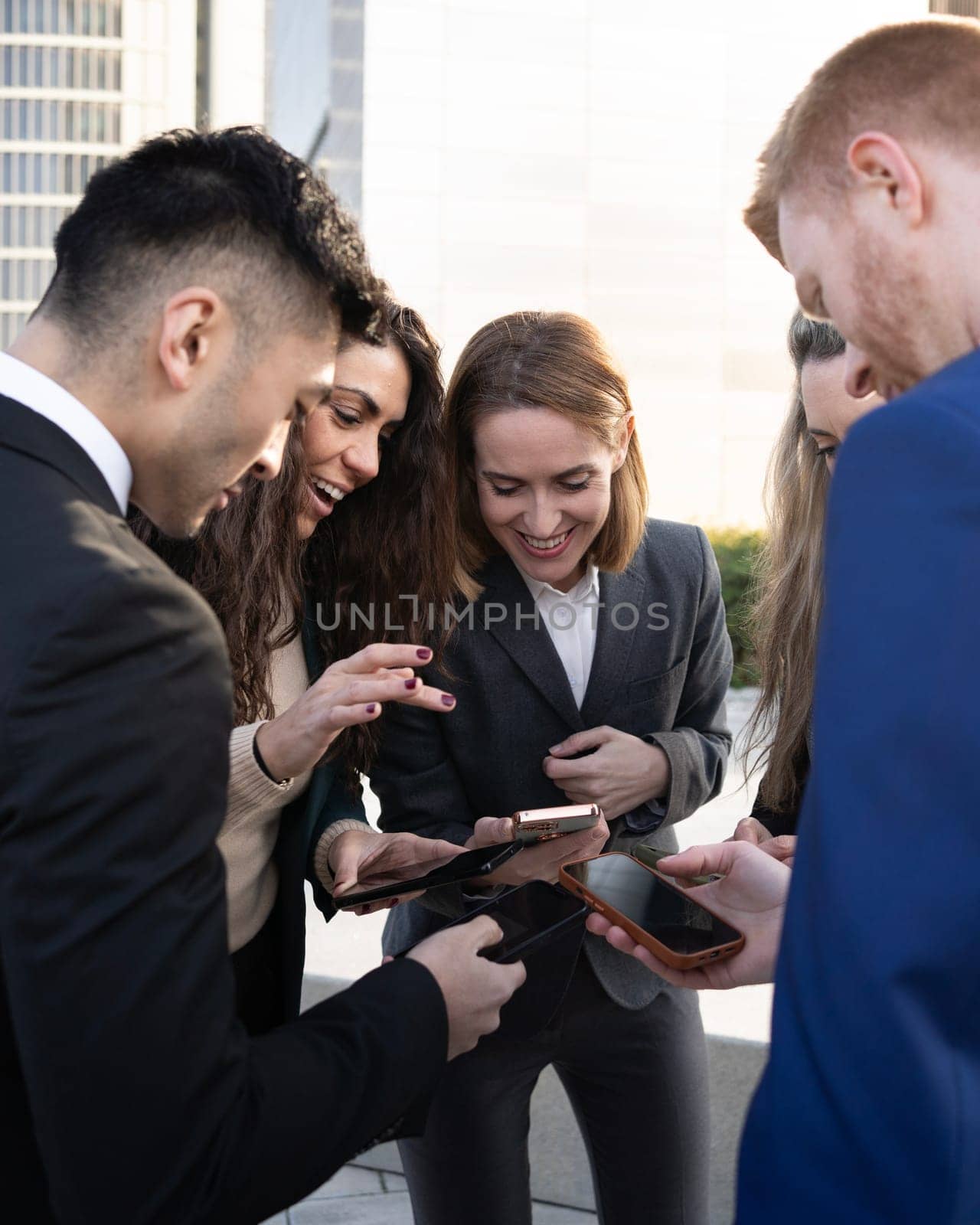 Group of people people are working together outdoors with their mobile devices on a business area by papatonic