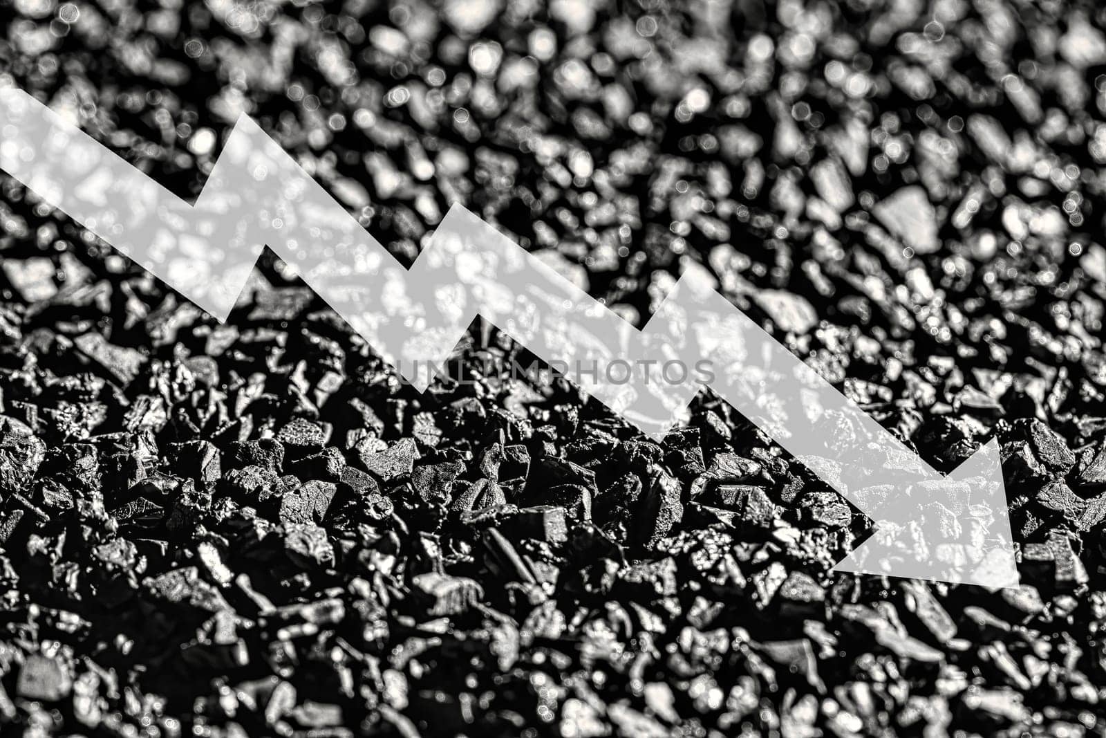 Arrow down on coal background. The concept of falling prices, mining, import, export, production, sales or supply of coal.