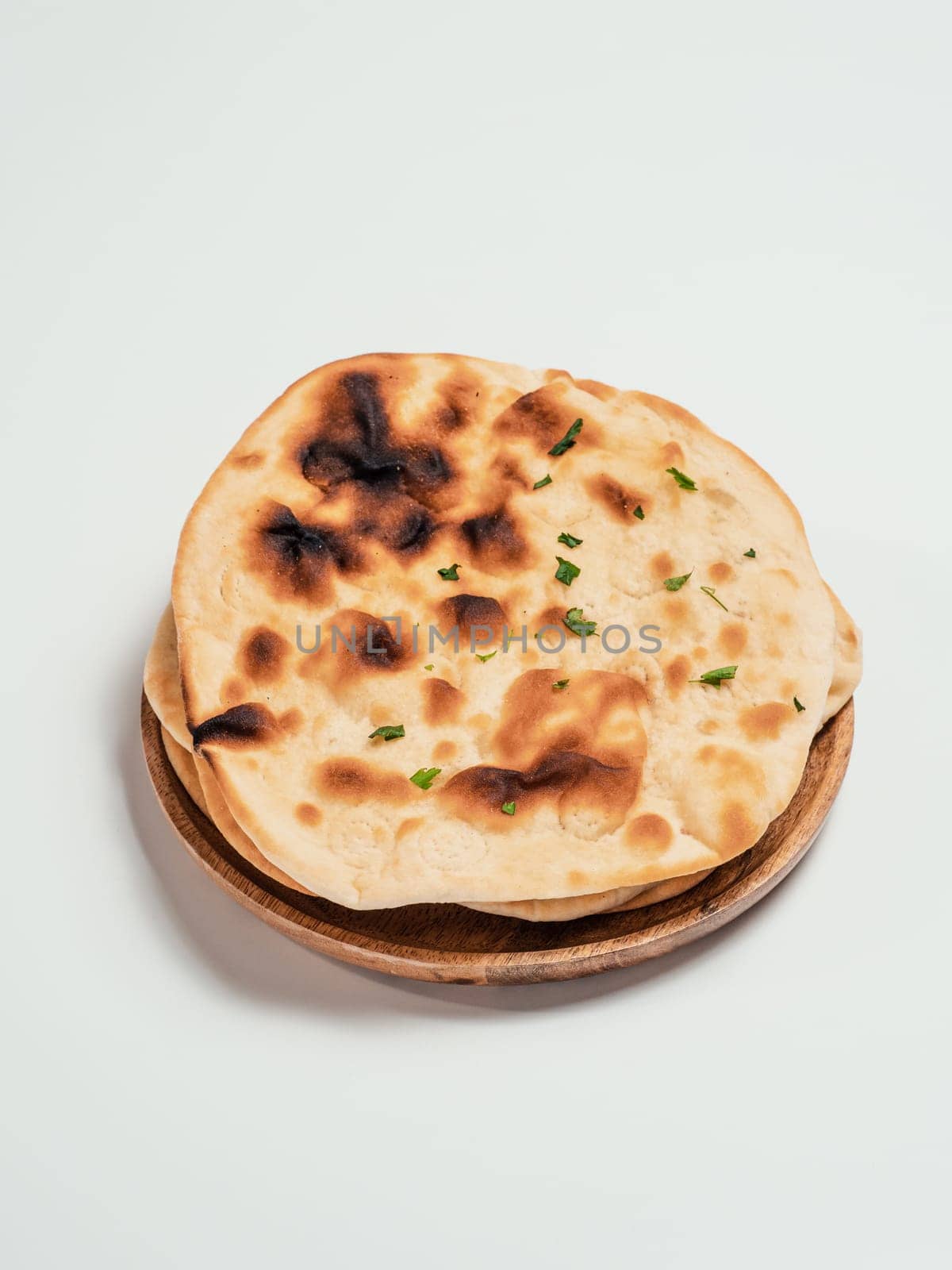 Fresh naan bread on plate isolated on white background. Stack of several perfect naan flatbreads on white.