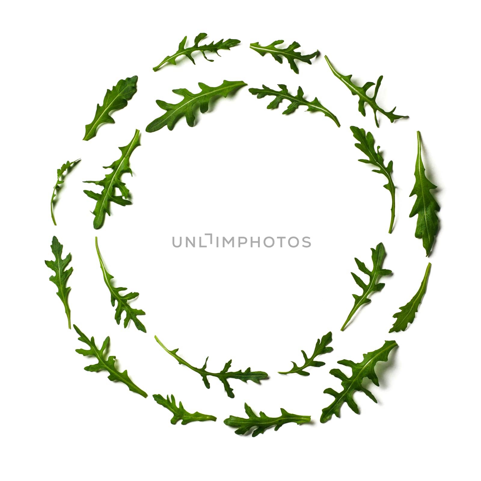 Pattern from arugula in round circle frame isolated. Circle shape in fresh green ruccola or arugula. Isolated on white with clipping path. Top view or flat lay. Can use for design vegan concept