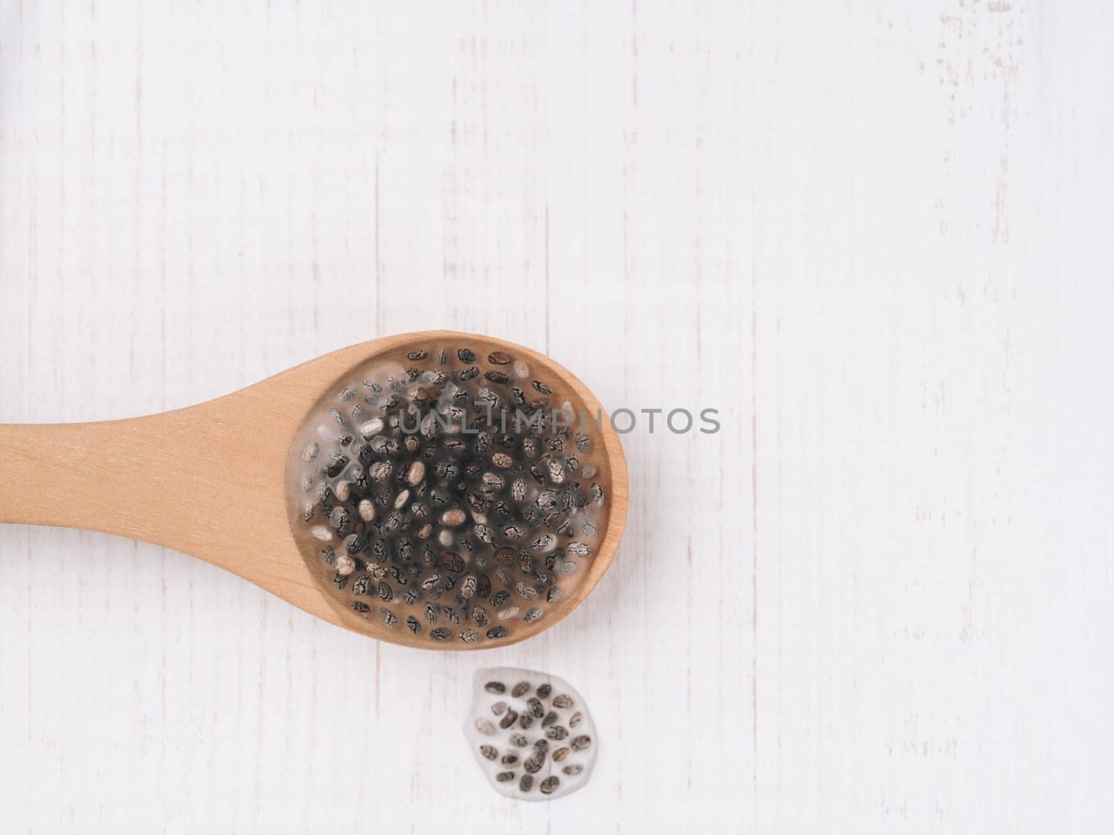 Wet chia seeds or chia-egg in wooden spoon on white wooden background. Egg replacers, plant based eggs, vegans replace eggs concept Copy space for text.