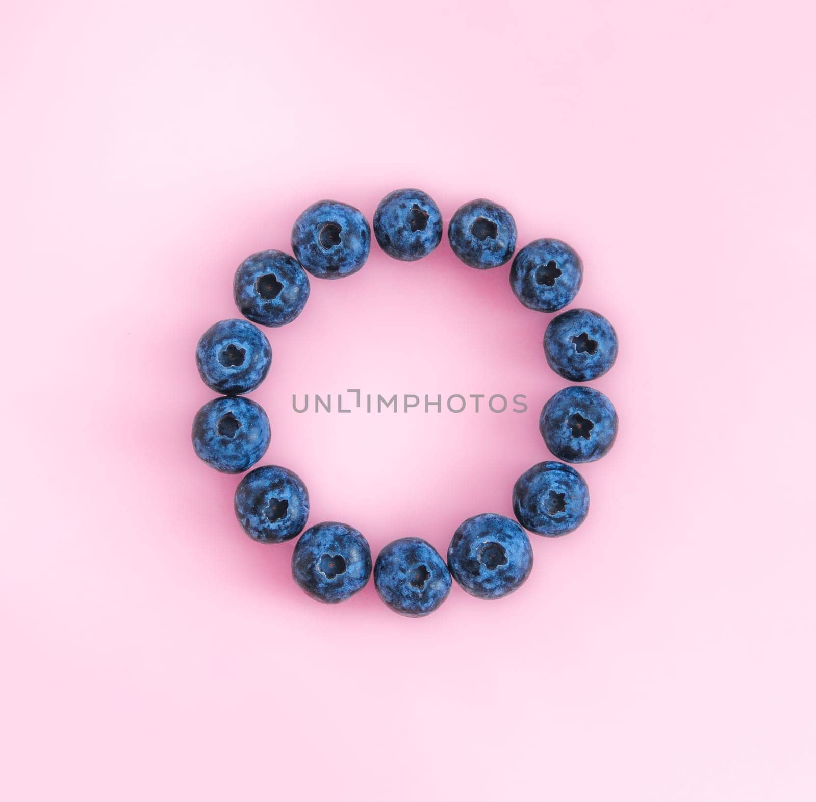 Creative layout with fresh ripe berries. Blueberry on pink background with round empty circle in center for copy space. Can use for your design, promo, social media, Top view. Square format for SMM.